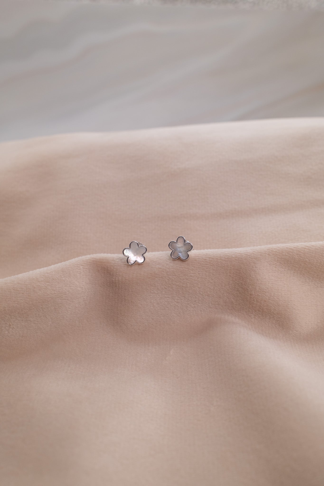 Zamari silver flower stud earrings displayed on beige fabric from online dainty jewelry boutique