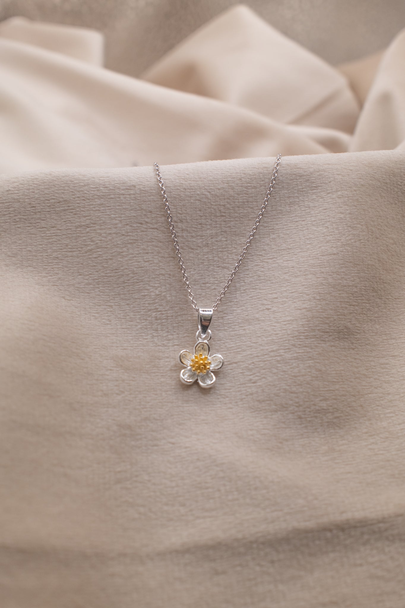Zamari delicate flower pendant necklace showcased by online dainty jewelry boutique on soft fabric