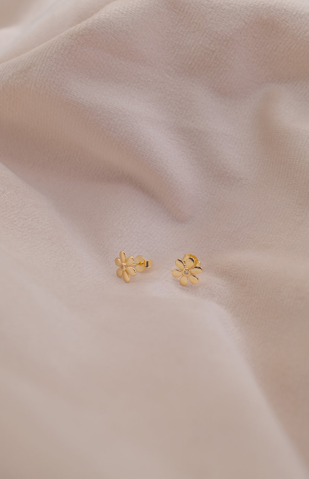 Zamari gold flower stud earrings displayed on soft fabric from online dainty jewelry boutique