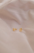 Zamari gold flower stud earrings displayed on soft fabric from online dainty jewelry boutique