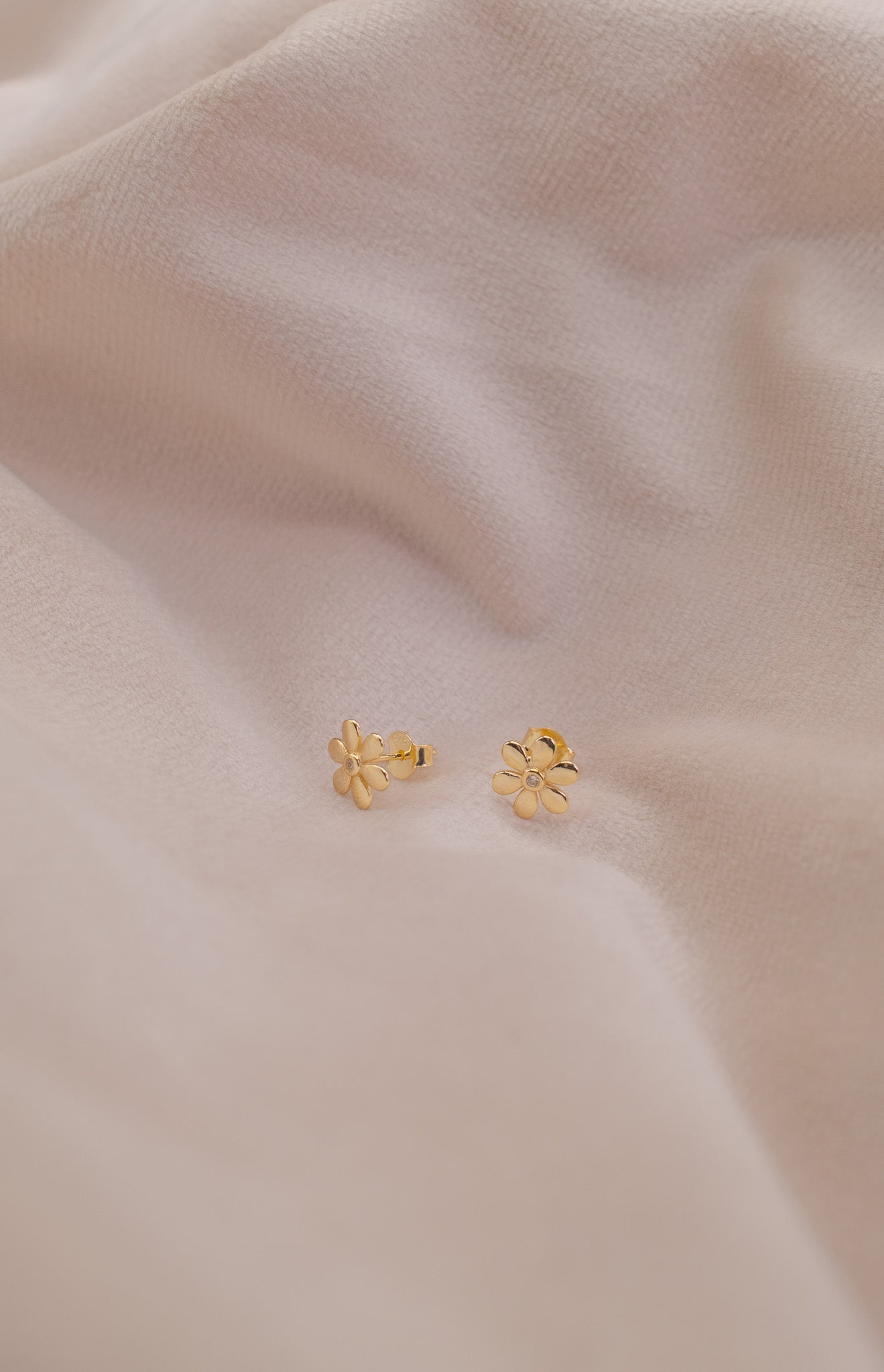Zamari gold flower stud earrings displayed on soft fabric from online dainty jewelry boutique