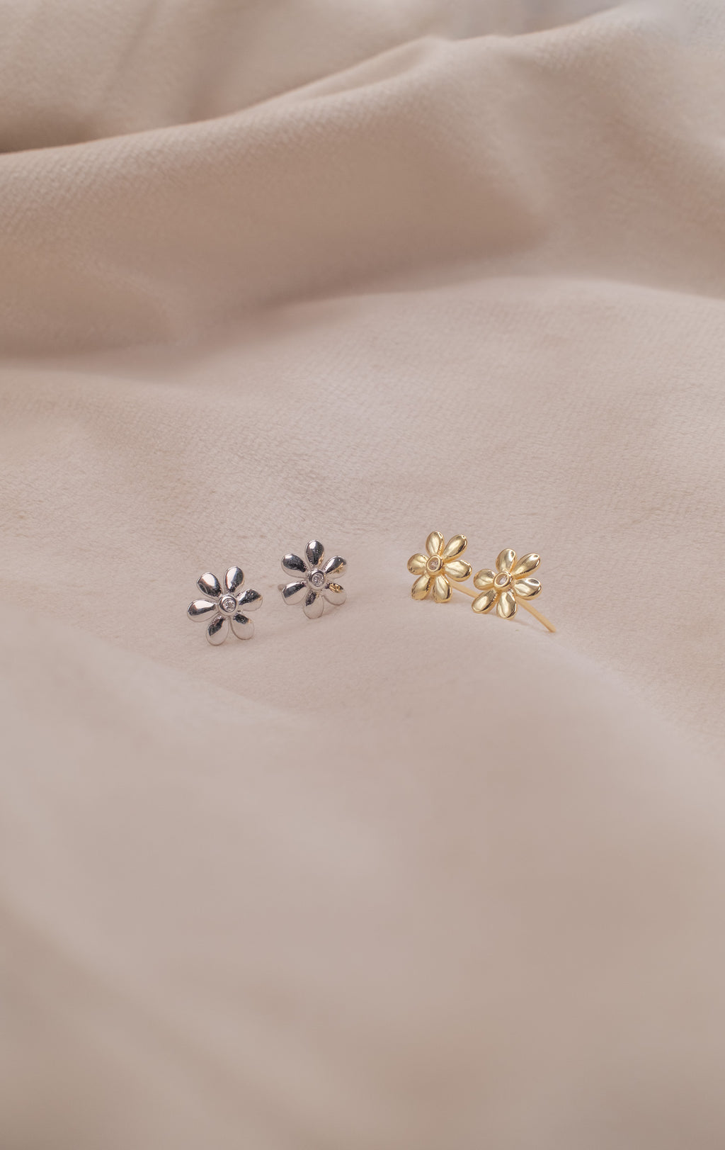 Zamari silver and gold flower earrings displayed on soft fabric from online dainty jewelry boutique