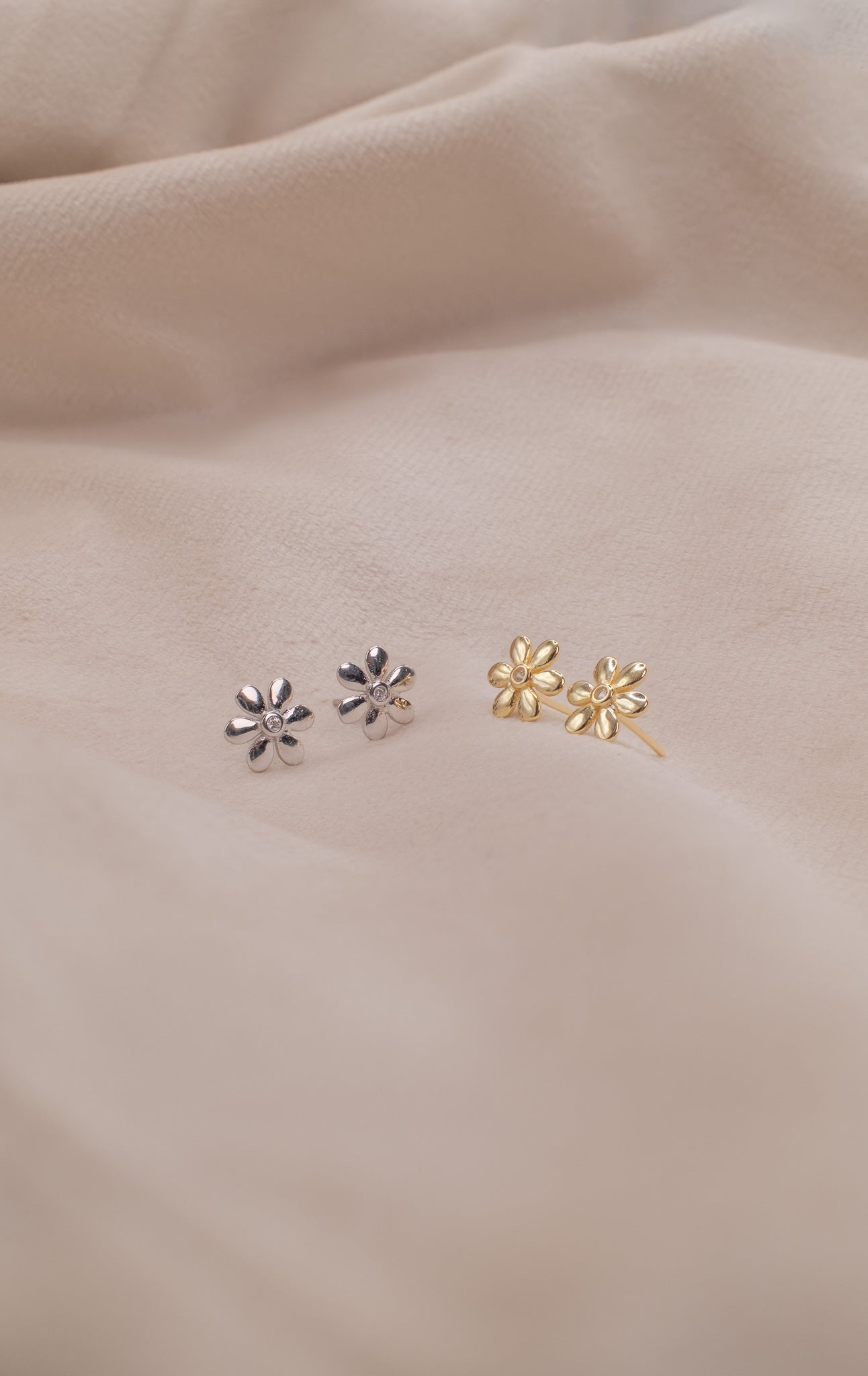 Zamari silver and gold flower earrings displayed on soft fabric from online dainty jewelry boutique