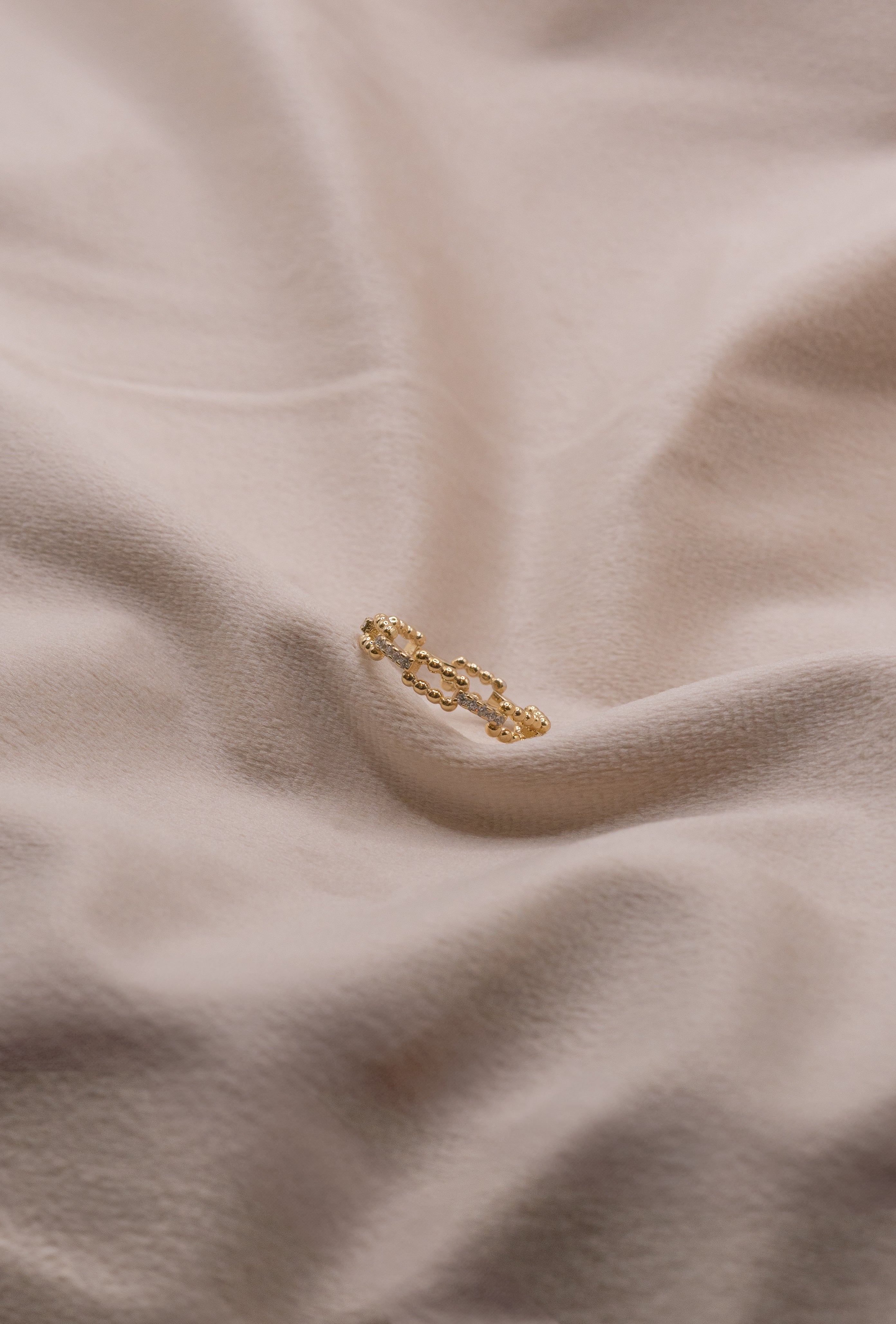 Gold chain link ring from Zamari displayed on soft beige fabric online dainty jewelry boutique