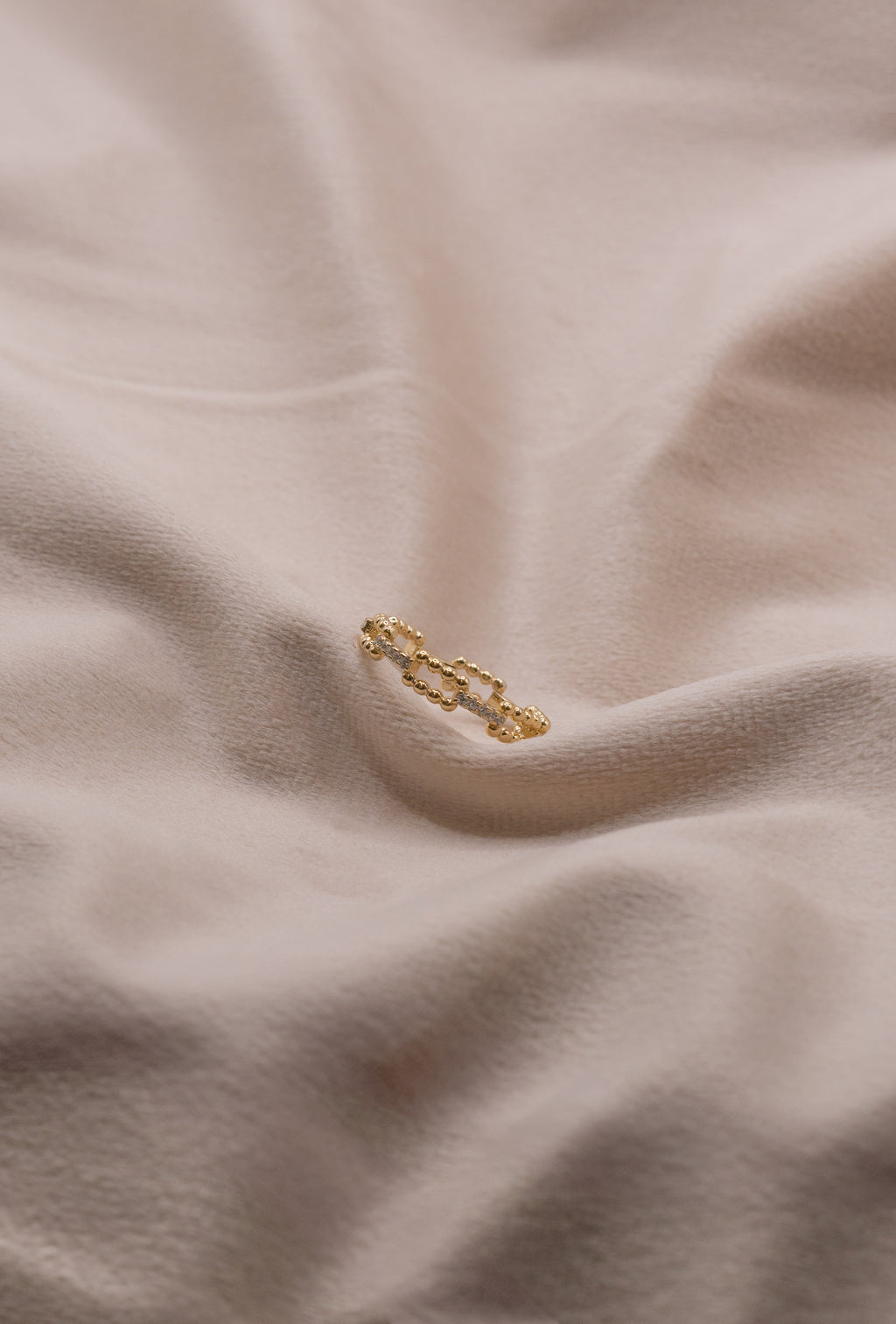 Gold chain link ring from Zamari displayed on soft beige fabric online dainty jewelry boutique