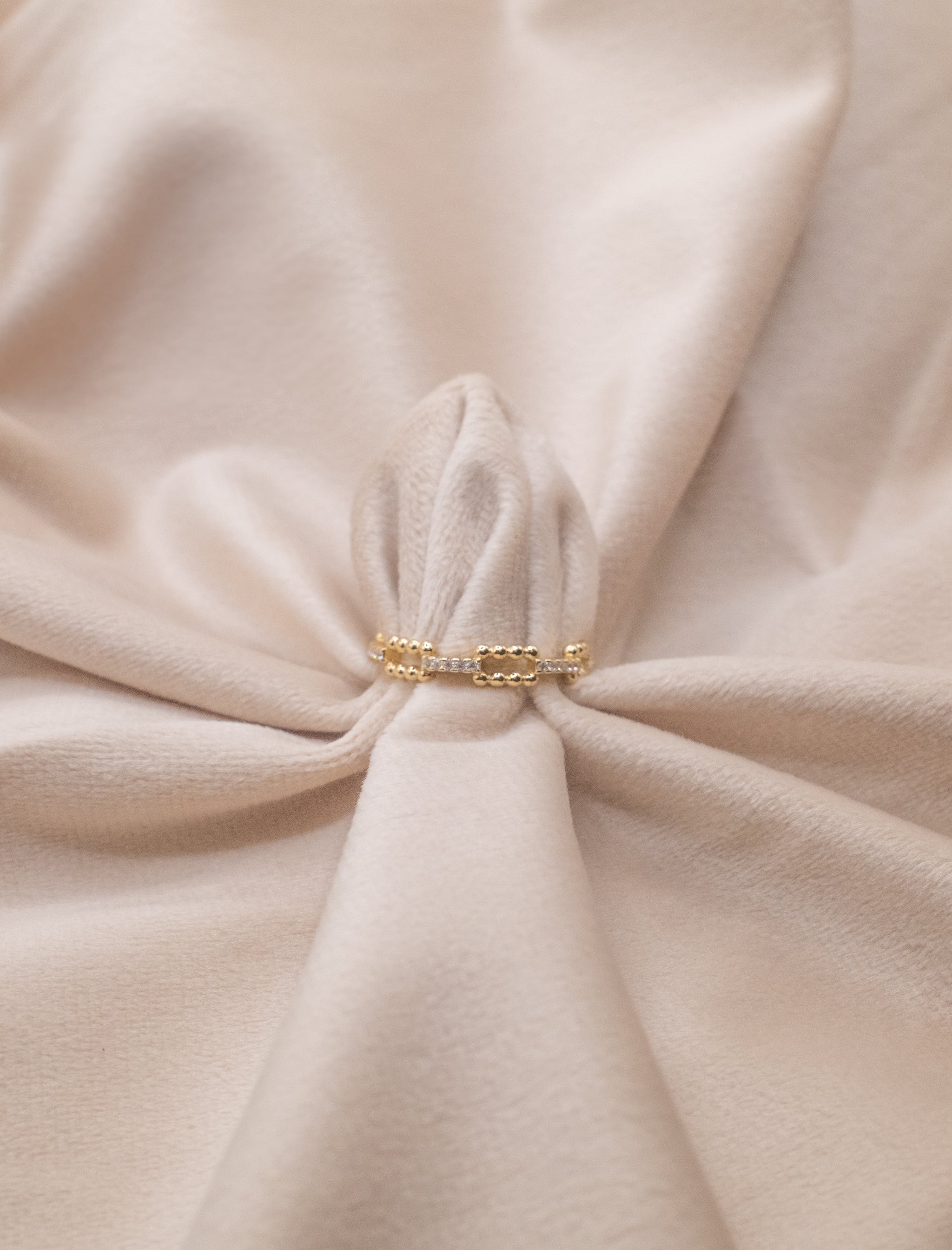 Golden delicate chain ring displayed on soft beige fabric from Zamari online dainty jewelry boutique