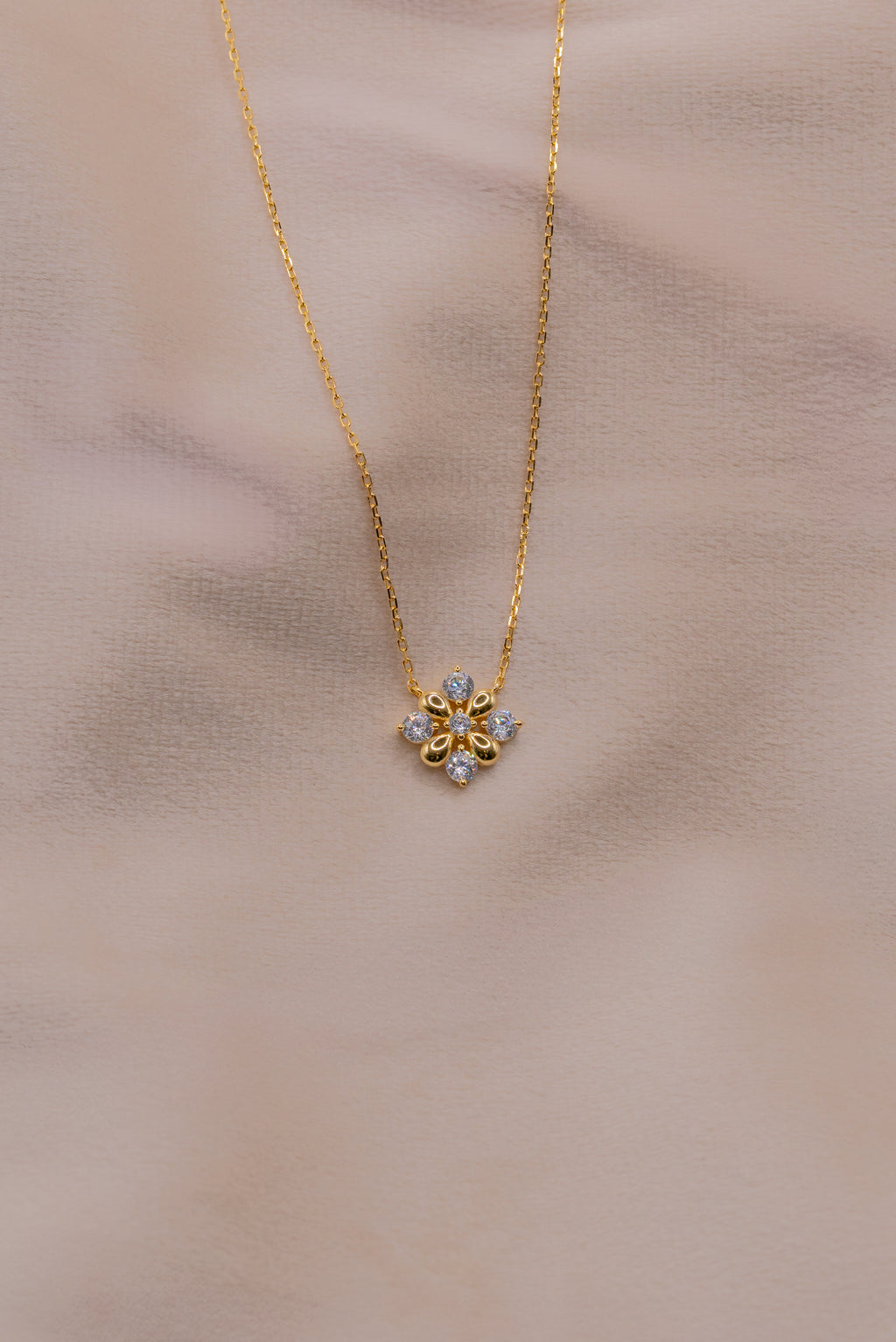 Zamari gold necklace with floral pendant from online dainty jewelry boutique on soft background