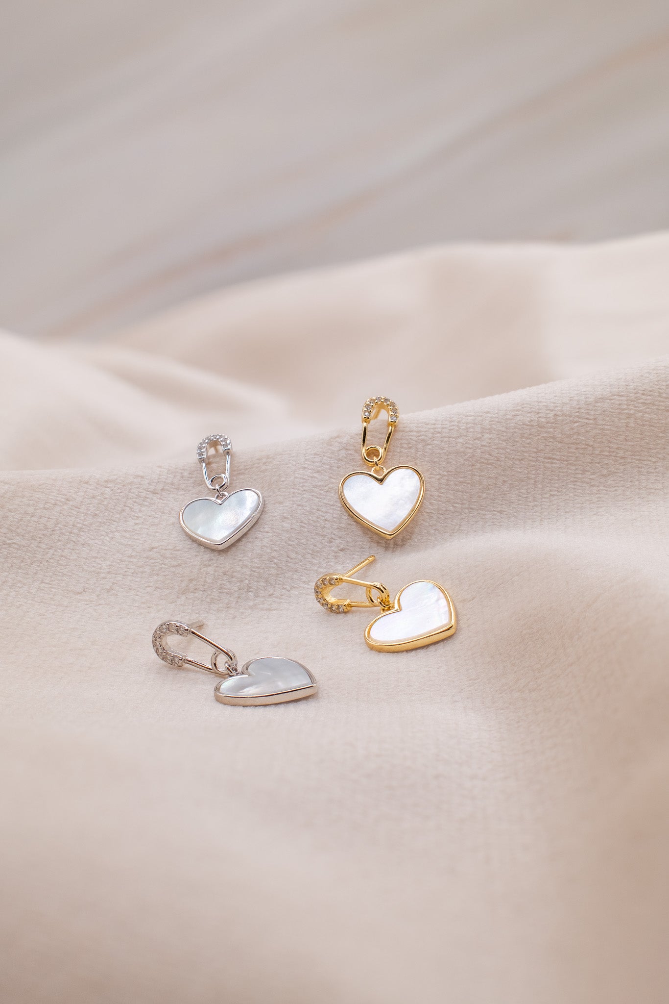 Zamari heart-shaped earrings in gold and silver on soft fabric from online dainty jewelry boutique