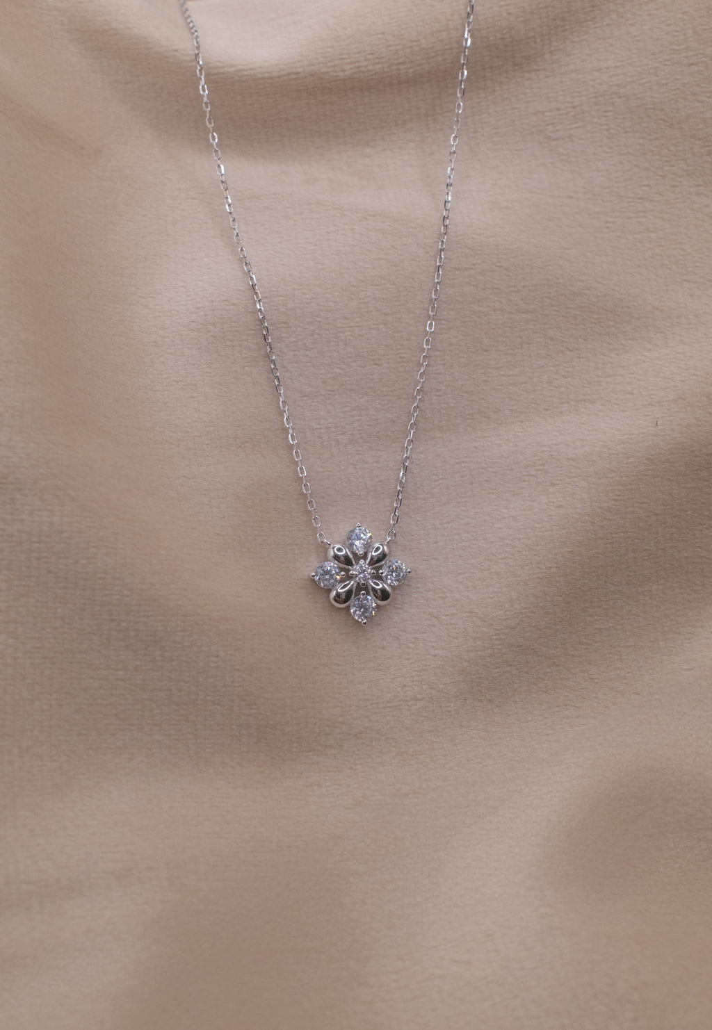 Zamari silver necklace with floral pendant from online dainty jewelry boutique on beige background