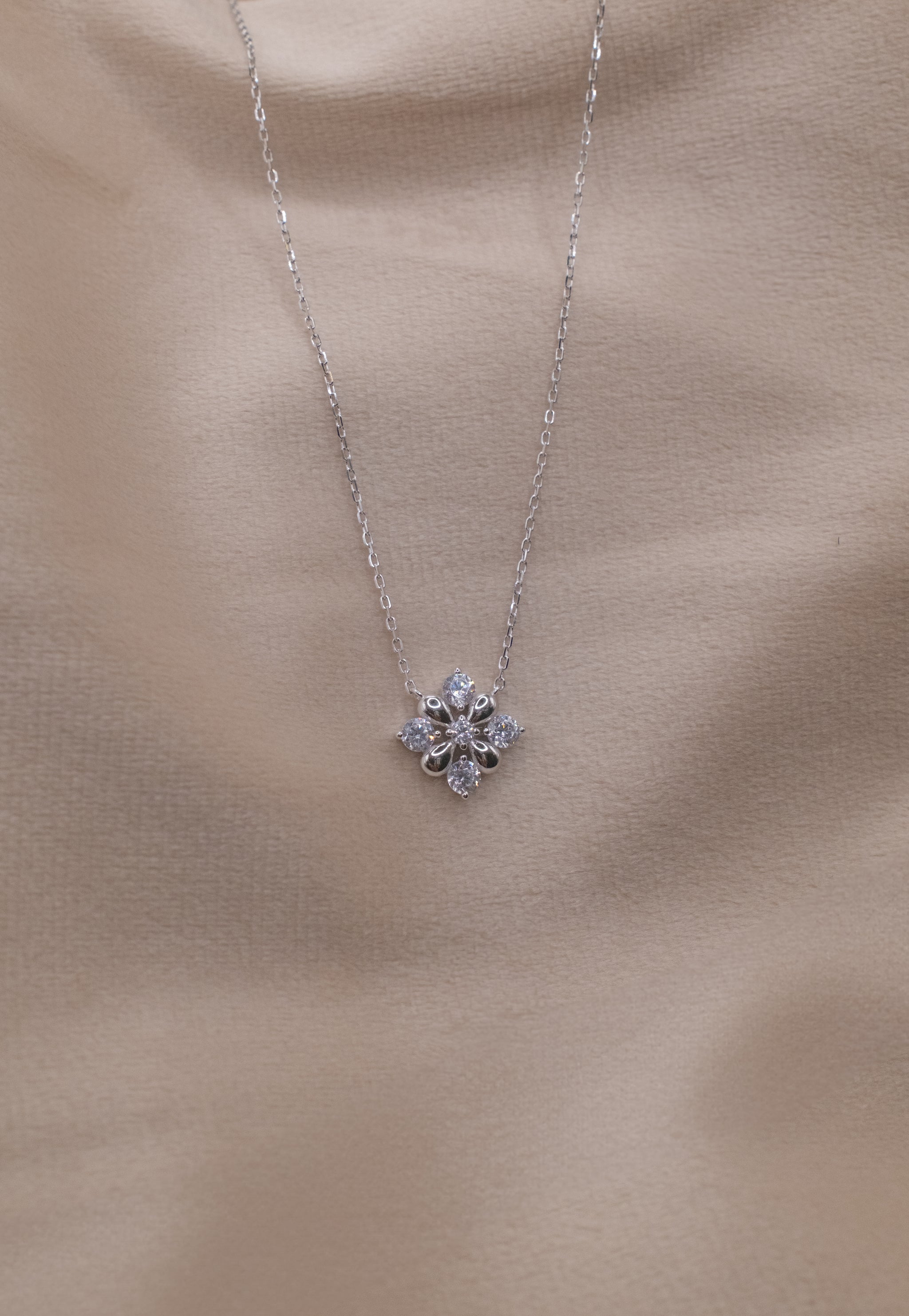 Zamari silver necklace with floral pendant from online dainty jewelry boutique on beige background