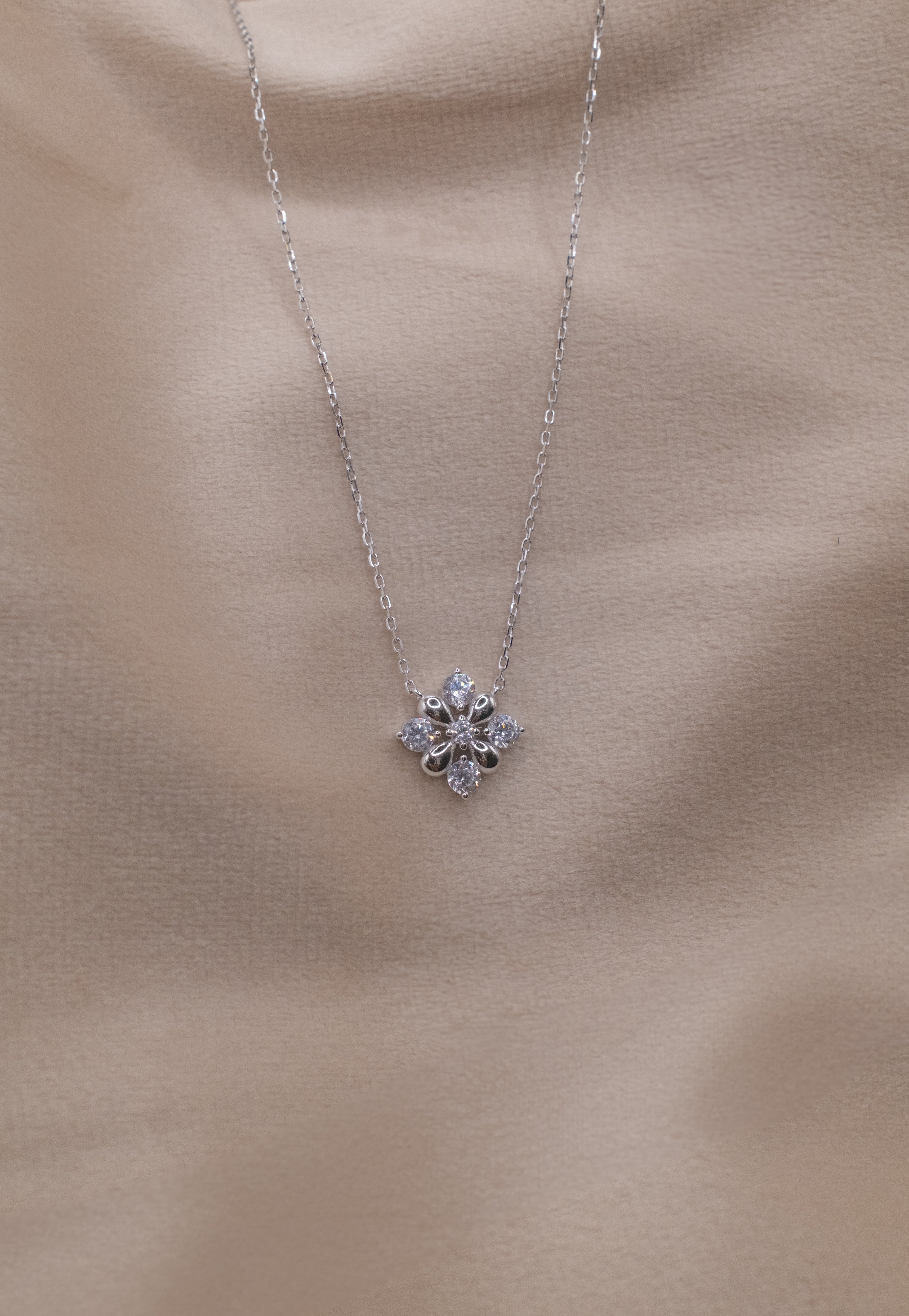 Zamari silver necklace with floral pendant from online dainty jewelry boutique on beige background