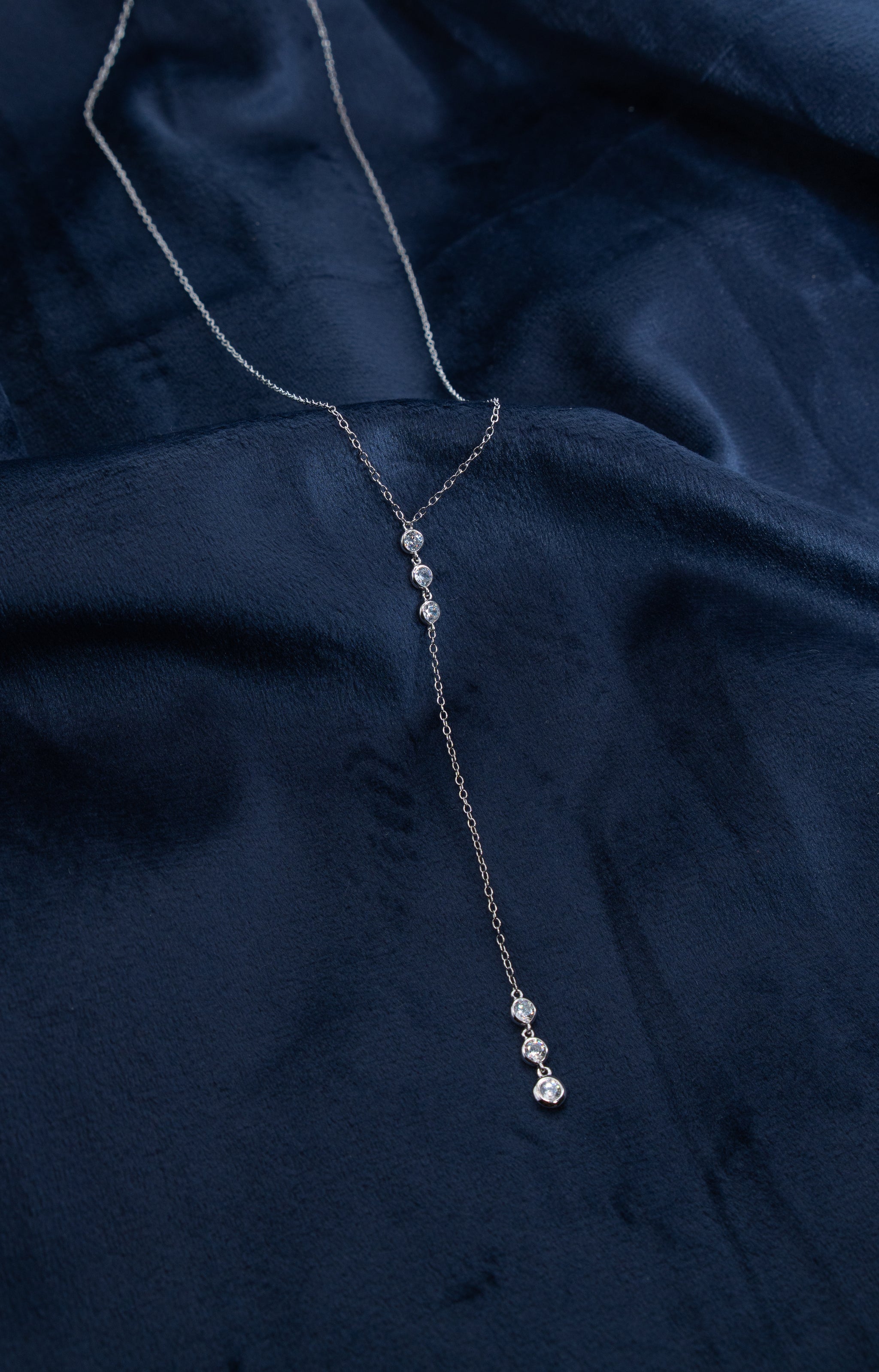Zamari silver necklace with crystal accents displayed on navy fabric from online dainty jewelry boutique
