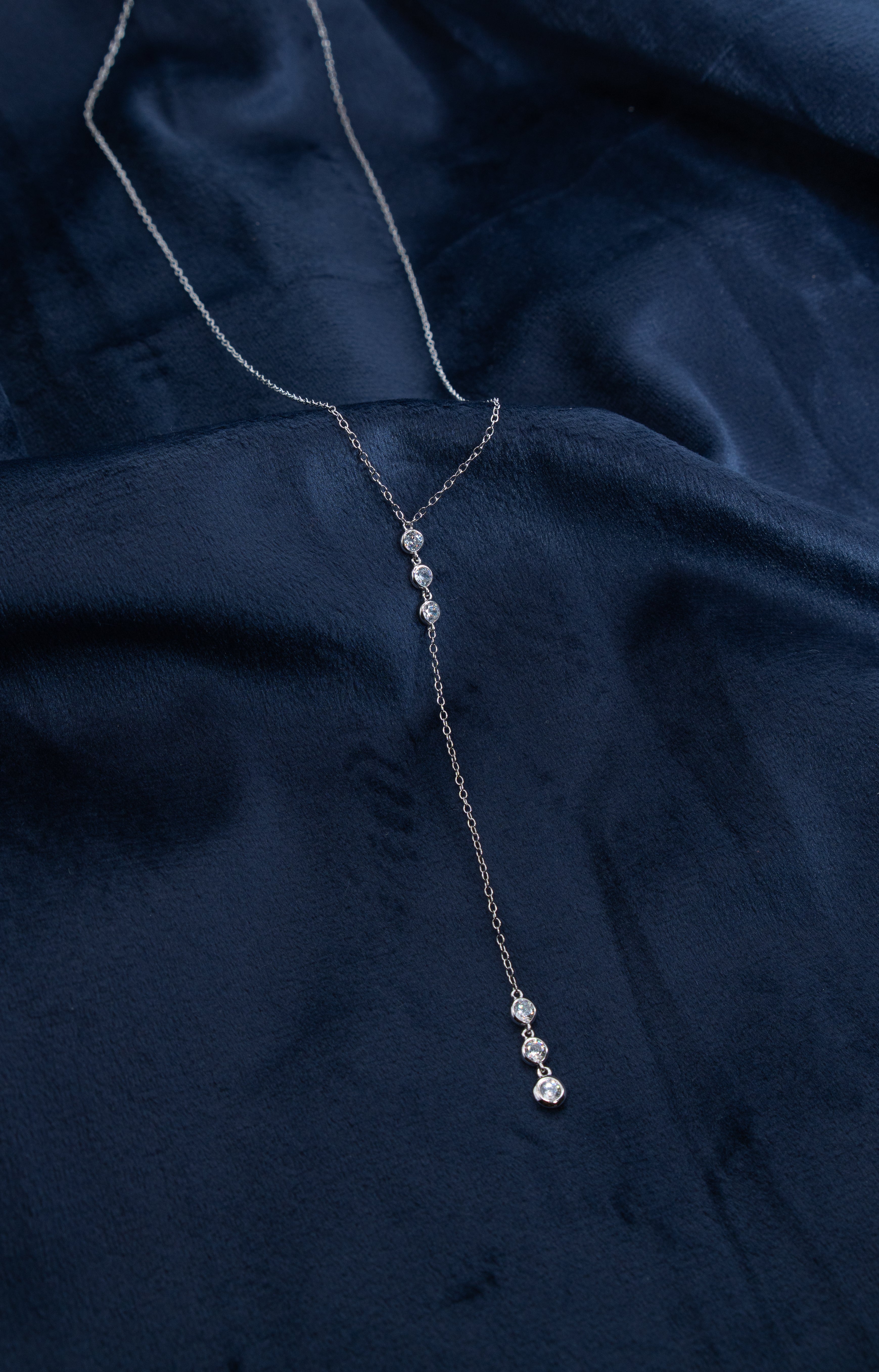 Zamari silver necklace with crystal accents displayed on navy fabric from online dainty jewelry boutique
