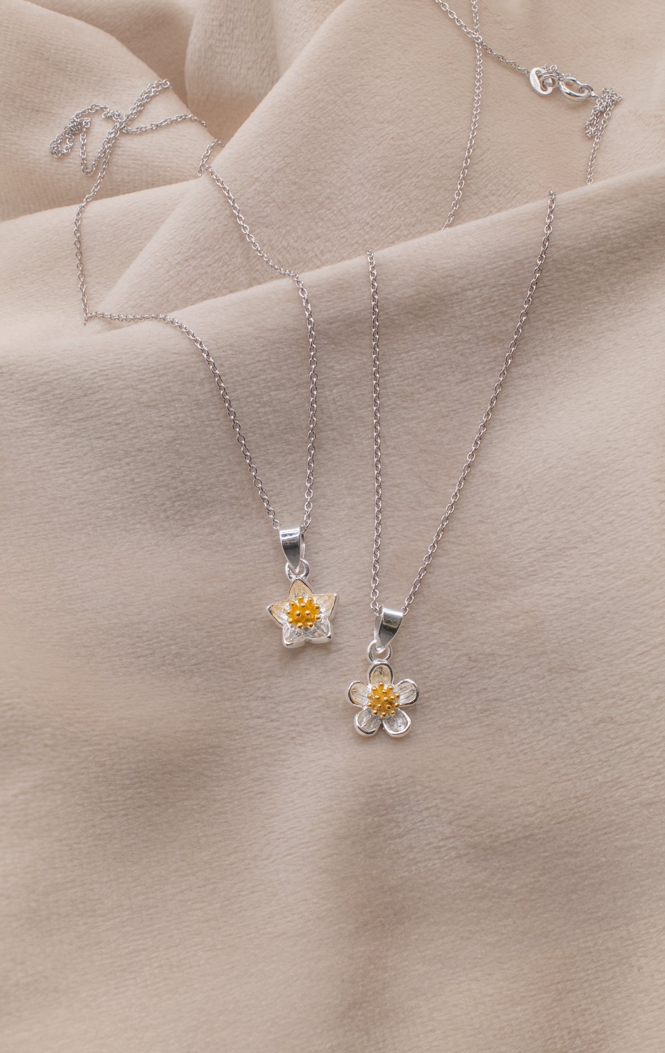 Zamari silver flower pendant necklaces displayed on beige fabric from online dainty jewelry boutique