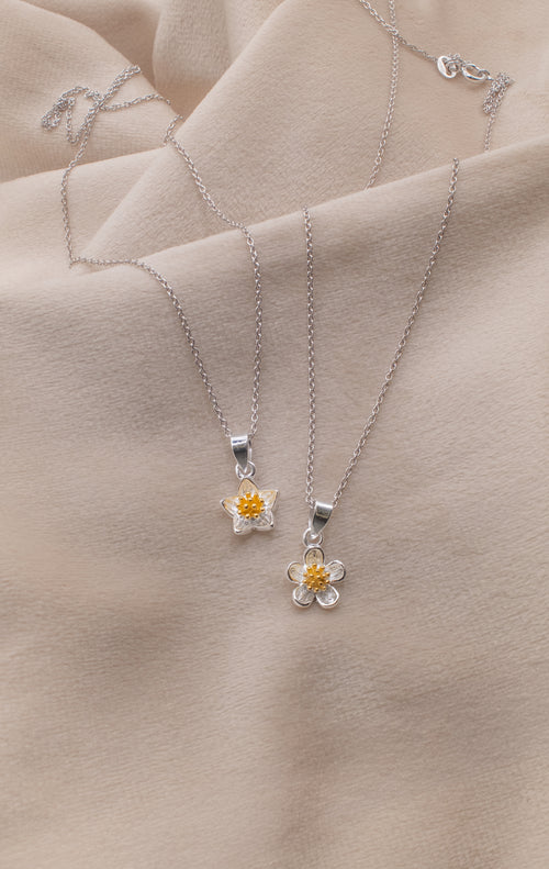 Zamari silver flower pendant necklaces displayed on beige fabric from online dainty jewelry boutique