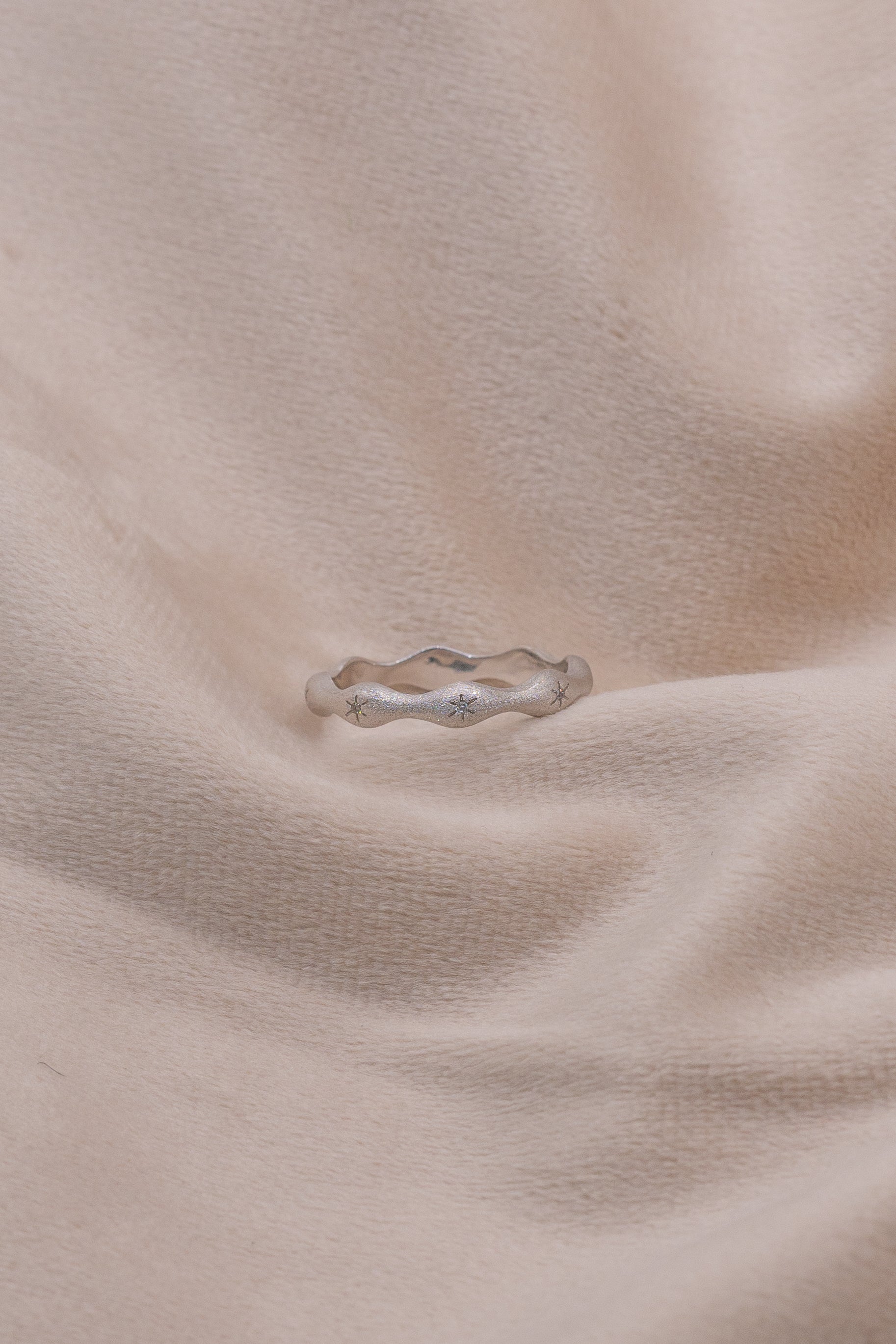 Zamari silver ring with wave design featured on soft fabric from online dainty jewelry boutique