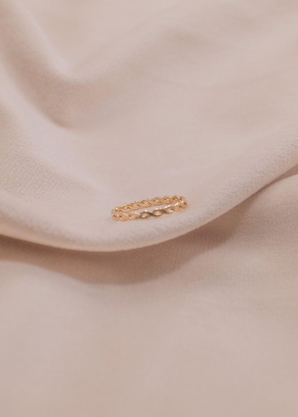 Zamari delicate twisted band ring styled on soft beige fabric for sterling silver jewelry collection