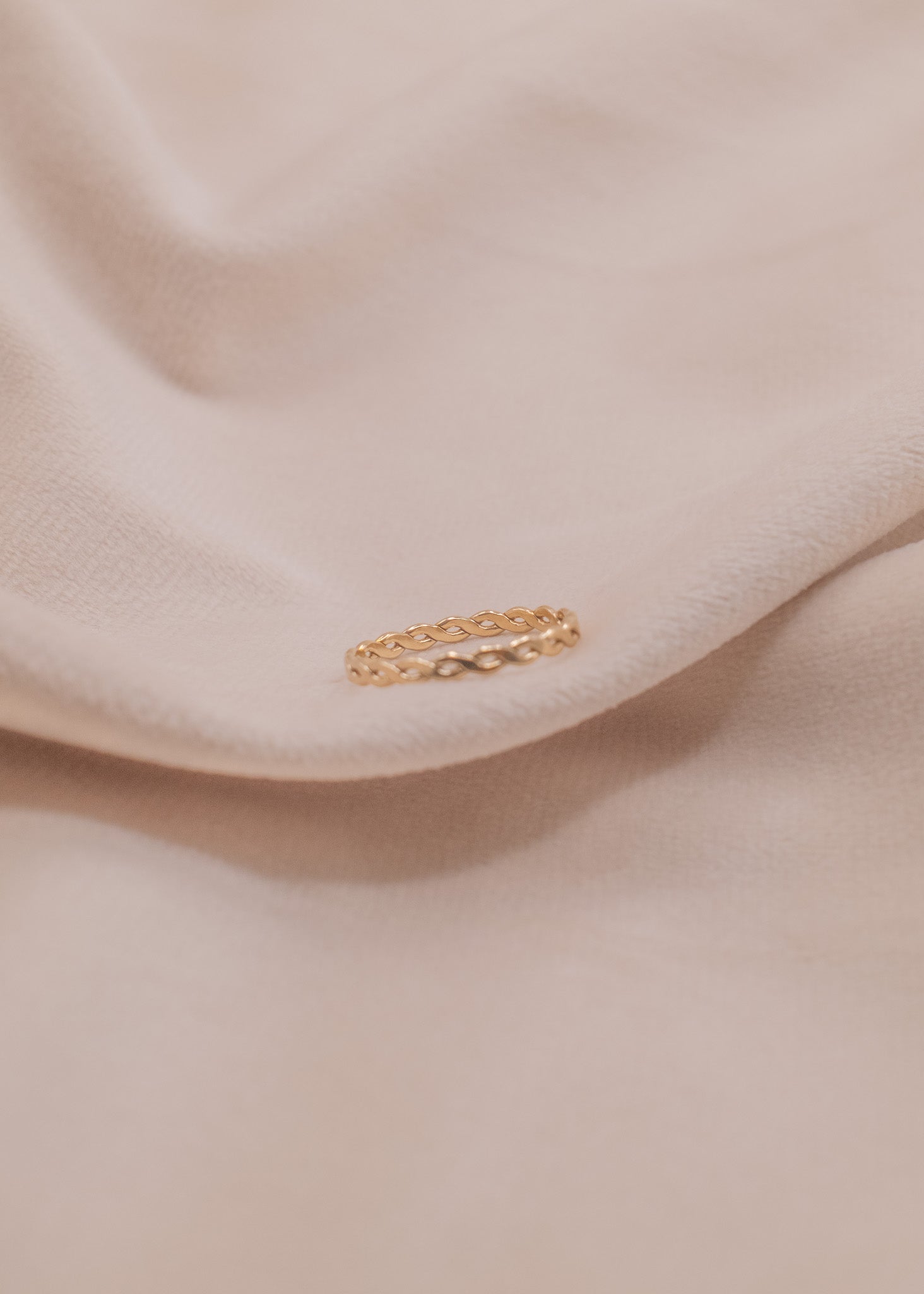 Zamari delicate twisted band ring styled on soft beige fabric for sterling silver jewelry collection