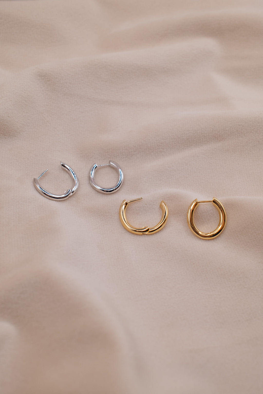 Zamari small hoop earrings in gold and silver tones showcasing sterling silver jewelry on beige fabric