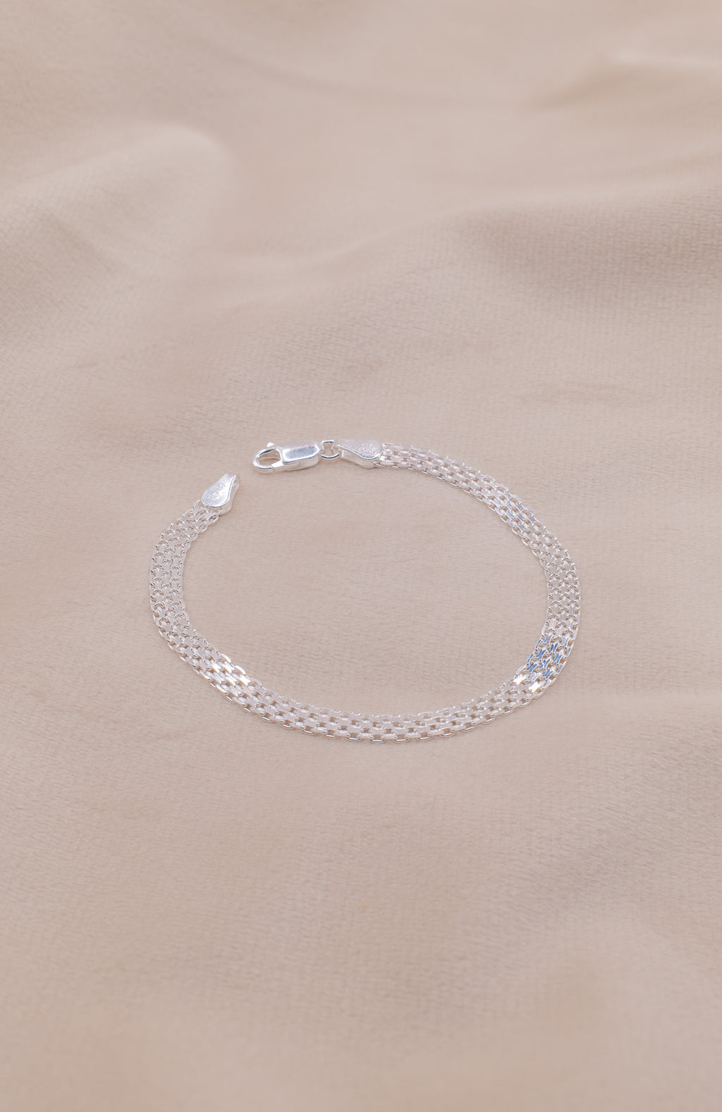 Zamari sterling silver jewelry bracelet with delicate chain design on beige fabric background