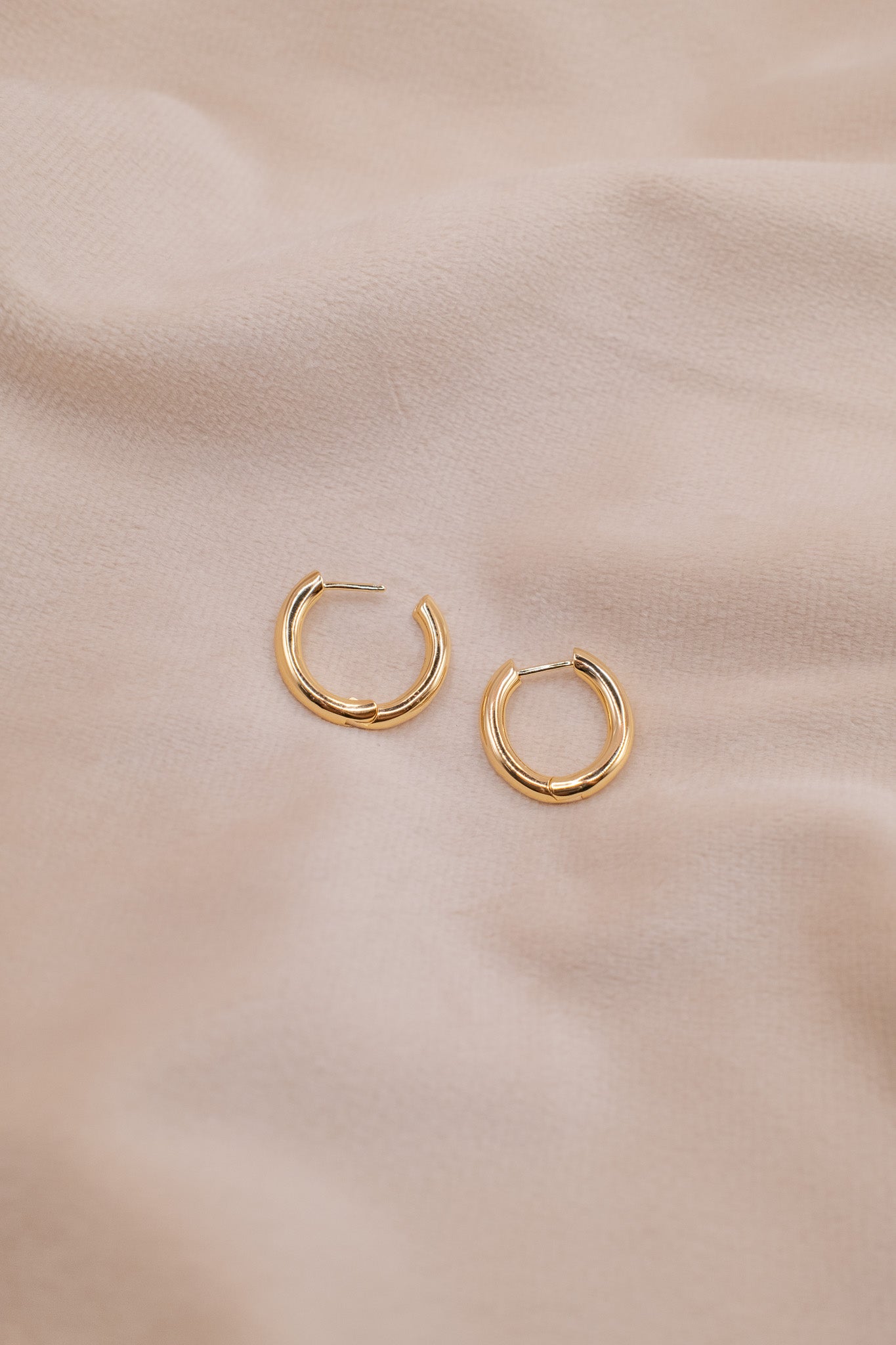 Zamari gold hoop earrings on beige fabric showcasing elegant sterling silver jewelry design