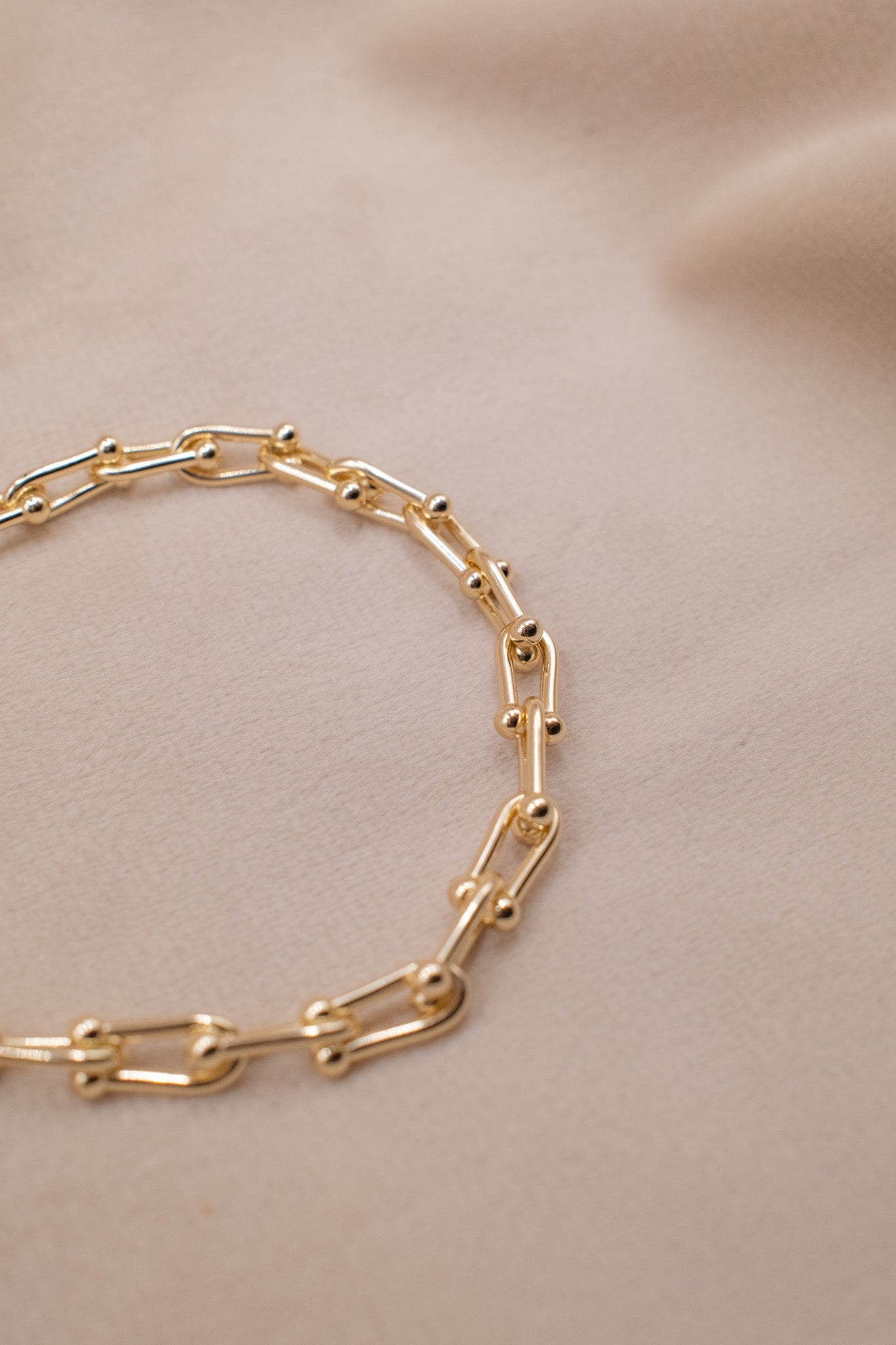 Zamari gold chain link bracelet from Sterling Silver Jewelry collection on beige fabric