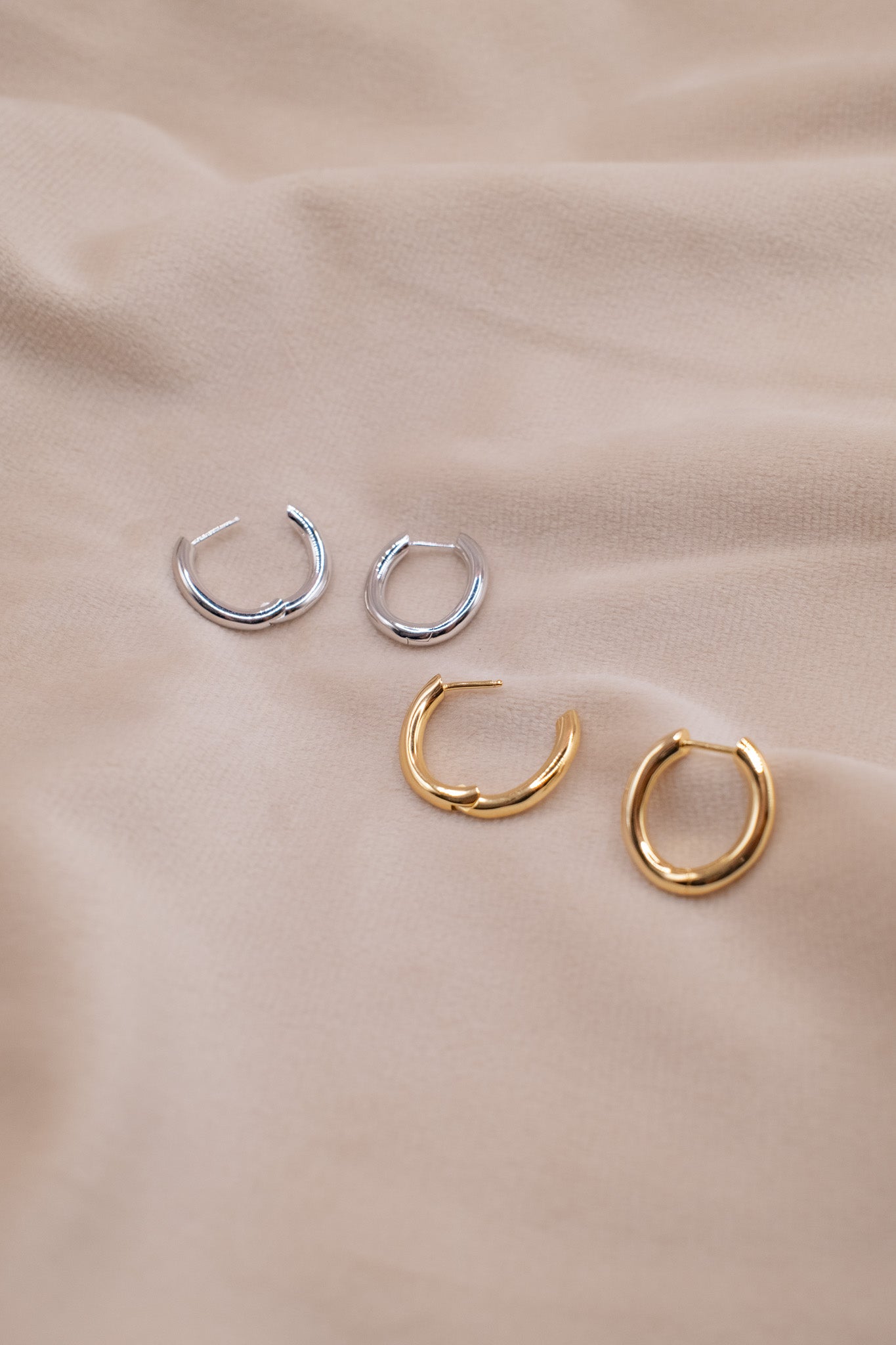 Zamari sterling silver jewelry hoop earrings in silver and gold displayed on beige fabric