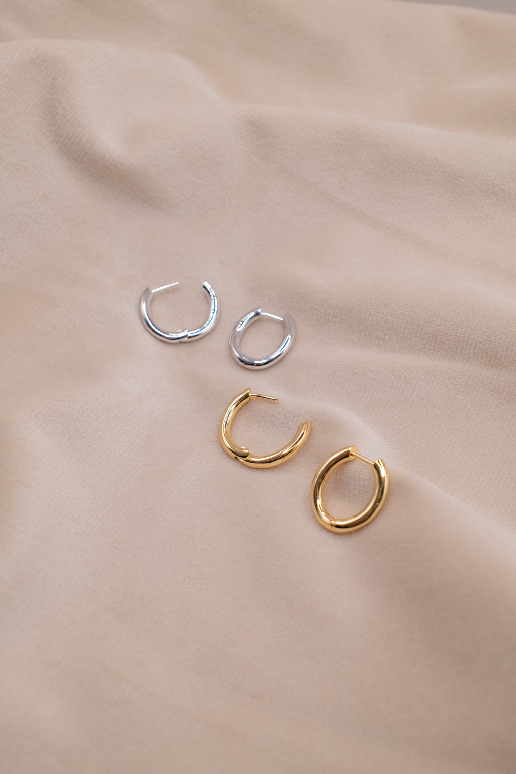 Zamari sterling silver jewelry small silver and gold hoop earrings displayed on beige fabric