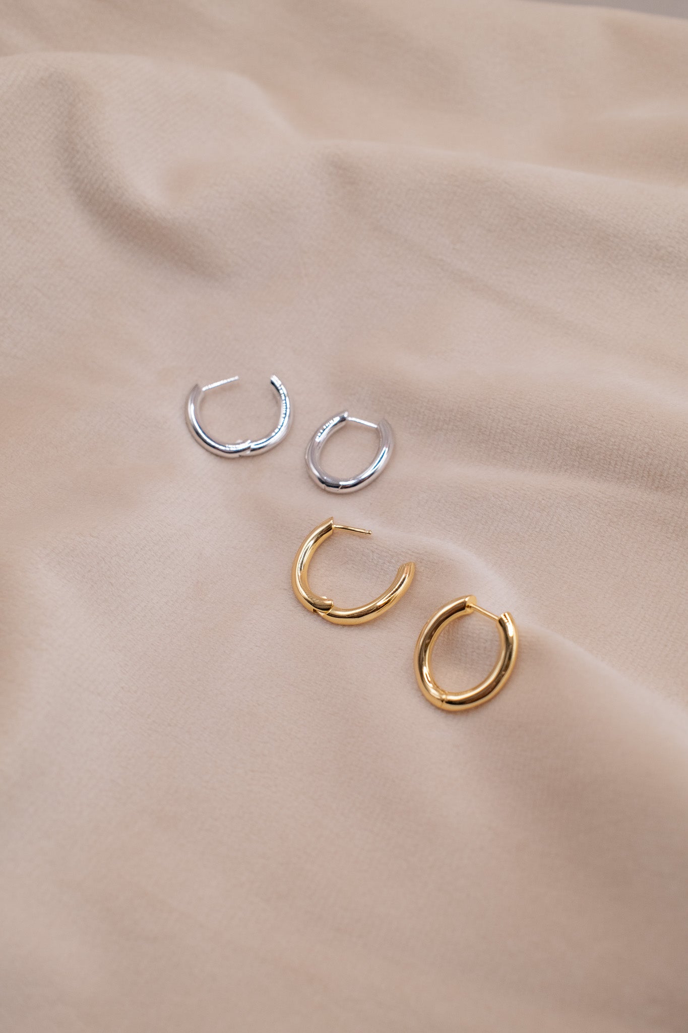 Zamari sterling silver jewelry small silver and gold hoop earrings displayed on beige fabric