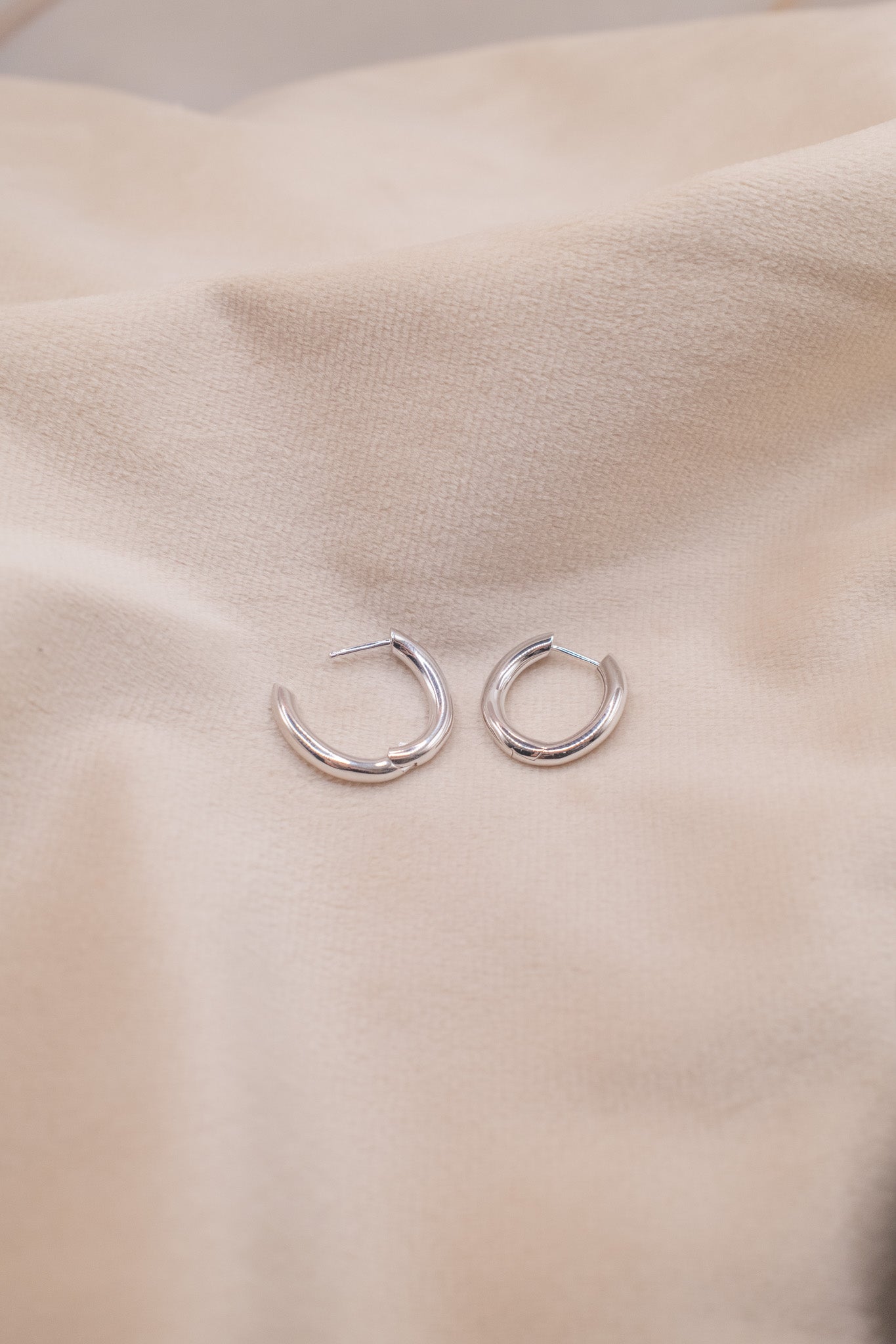 Zamari sterling silver jewelry hoop earrings displayed on beige fabric background