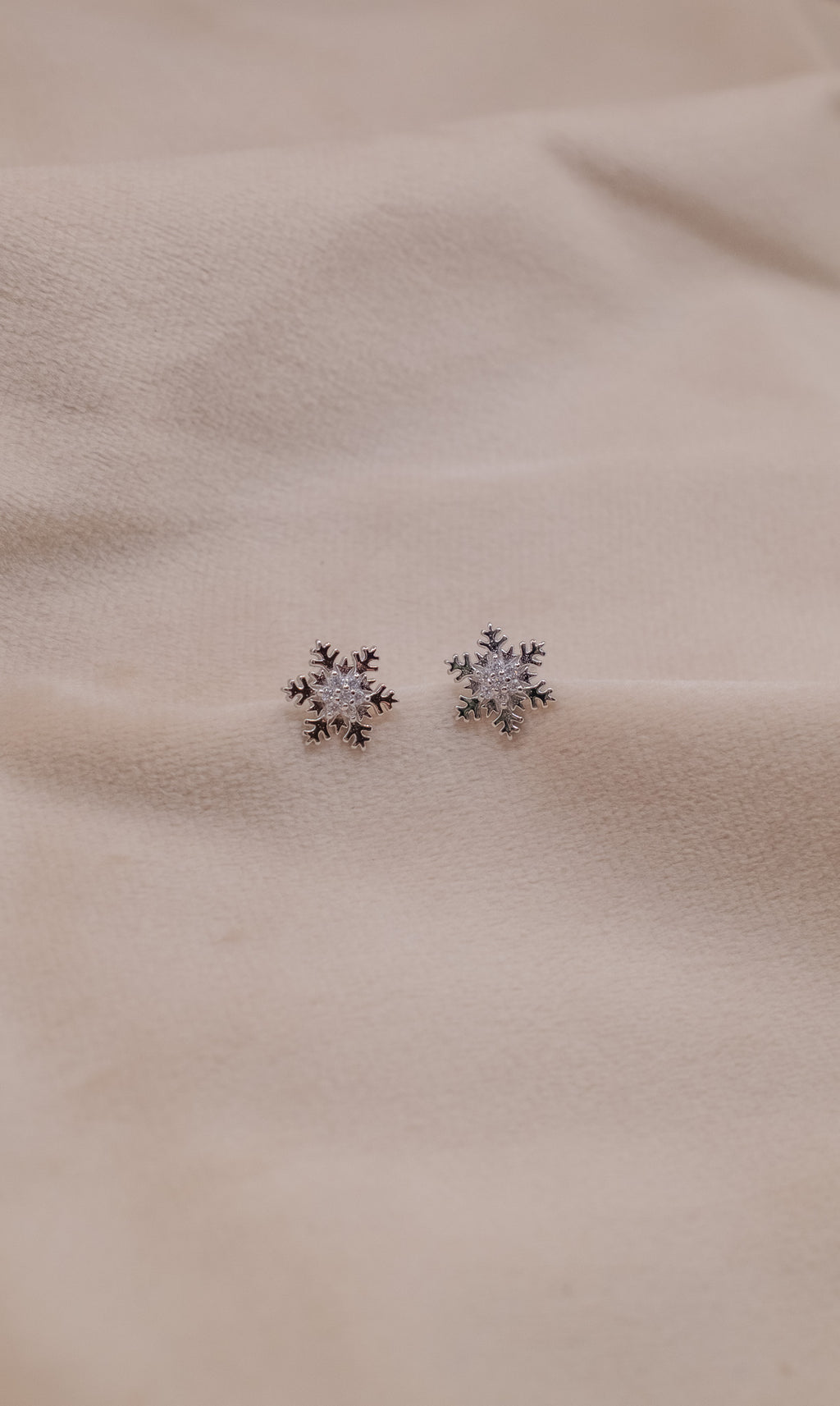 Zamari snowflake stud earrings crafted in sterling silver jewelry design on beige fabric