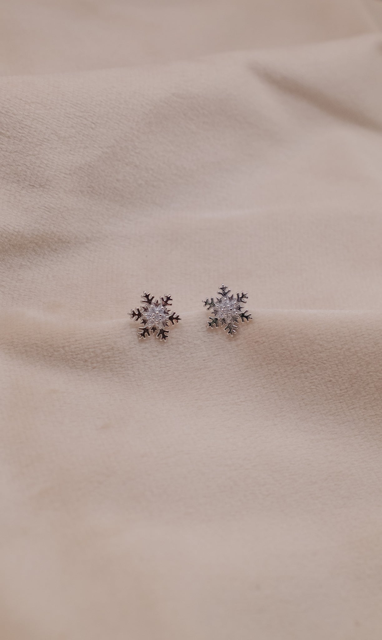 Zamari snowflake stud earrings crafted in sterling silver jewelry design on beige fabric
