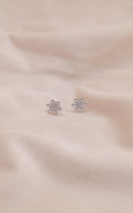 Zamari sterling silver jewelry snowflake stud earrings on soft beige fabric background